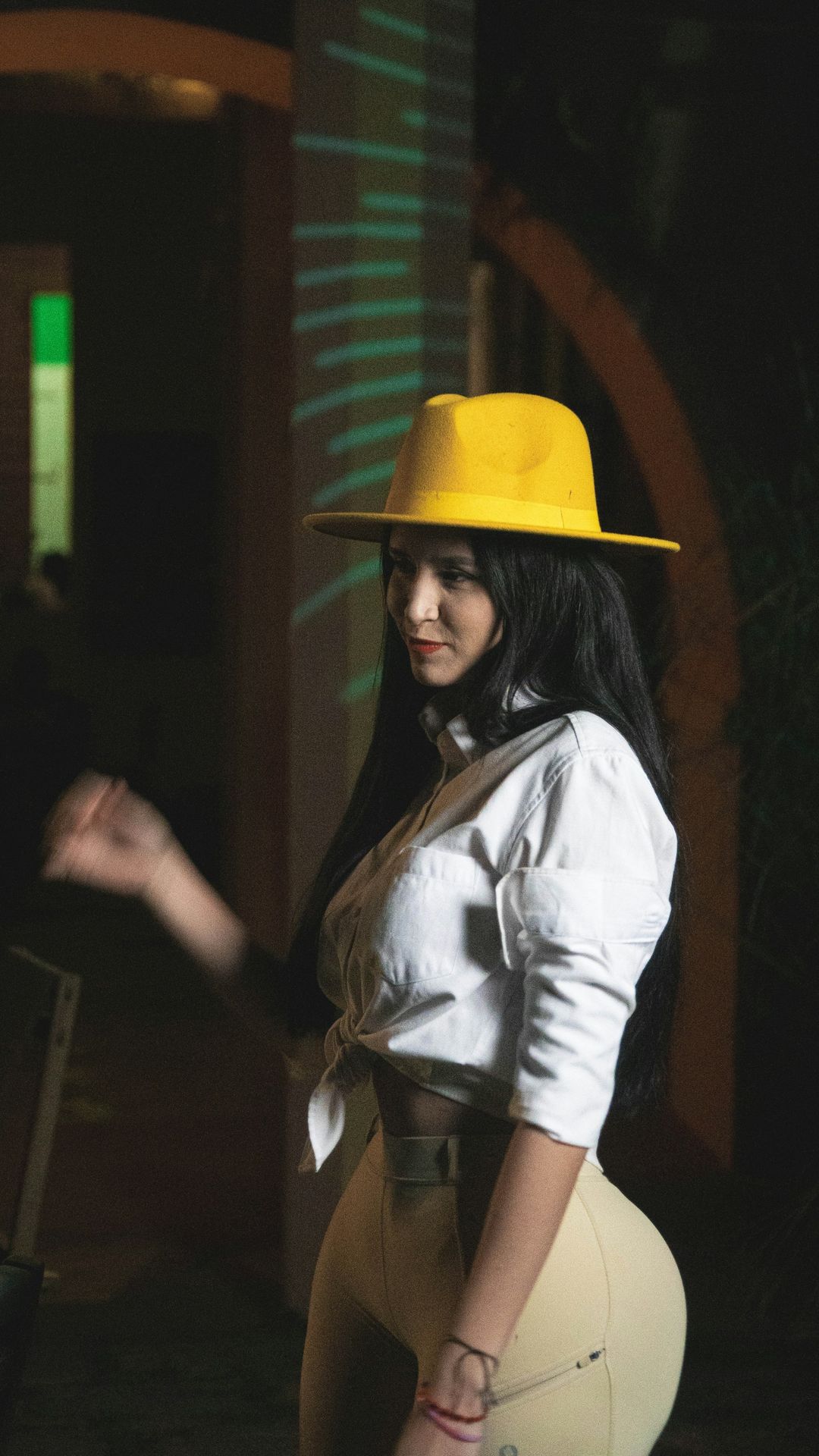 A woman in a yellow hat is posing for a picture